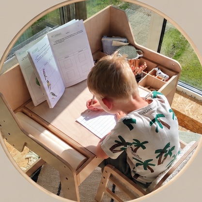 A child absorbed in drawing at a Luula table